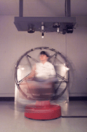 Click to view an image of a research subject sitting in a motion sickness chair during a NASA Psychophysiology Lab research study